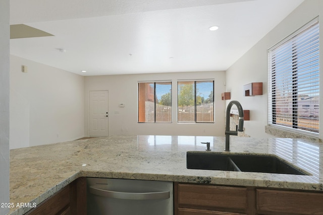 kitchen with light stone counters, sink, and stainless steel dishwasher