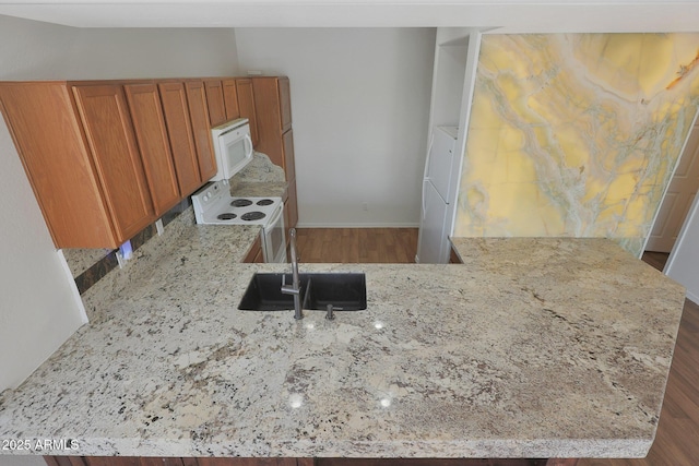 kitchen featuring kitchen peninsula, white appliances, and light stone counters