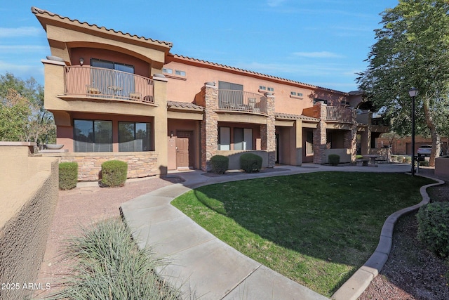 exterior space featuring a balcony and a front yard