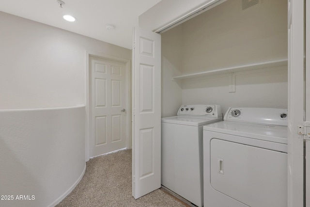 clothes washing area with light carpet and washer and dryer