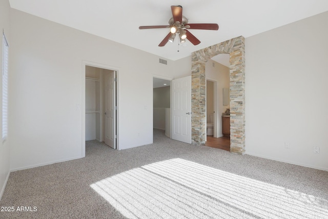 unfurnished bedroom with carpet flooring, a walk in closet, a closet, and ceiling fan