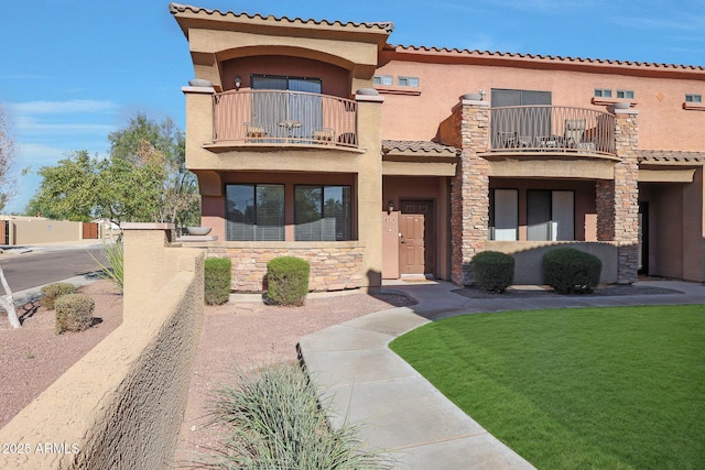 mediterranean / spanish house featuring a balcony and a front lawn