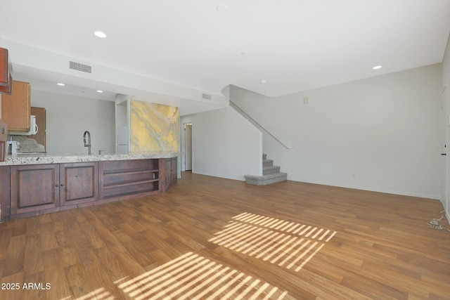 unfurnished living room featuring hardwood / wood-style flooring and sink