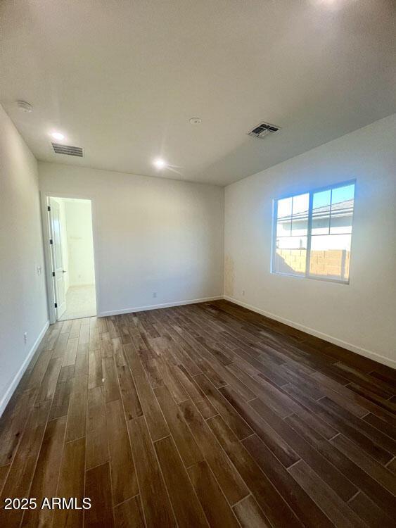 unfurnished room with visible vents, baseboards, and dark wood-style flooring