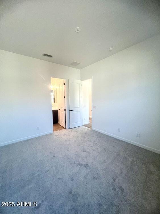 unfurnished bedroom with light carpet, visible vents, ensuite bathroom, and baseboards