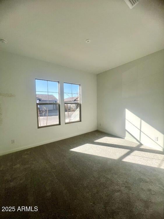 unfurnished room featuring carpet and baseboards