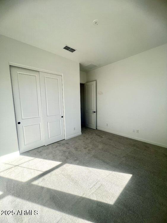 unfurnished bedroom featuring visible vents, baseboards, a closet, and carpet flooring