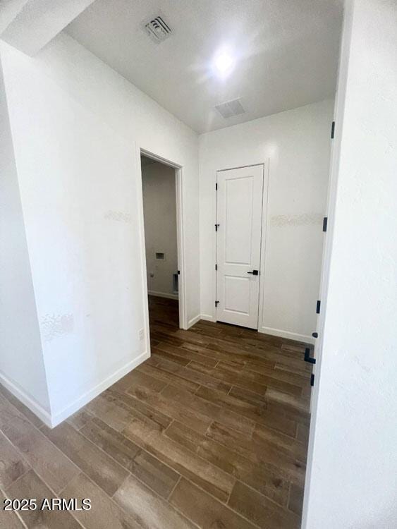 hallway with visible vents, baseboards, and wood finished floors