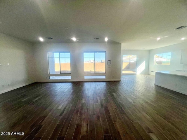 unfurnished living room featuring visible vents, baseboards, and dark wood finished floors