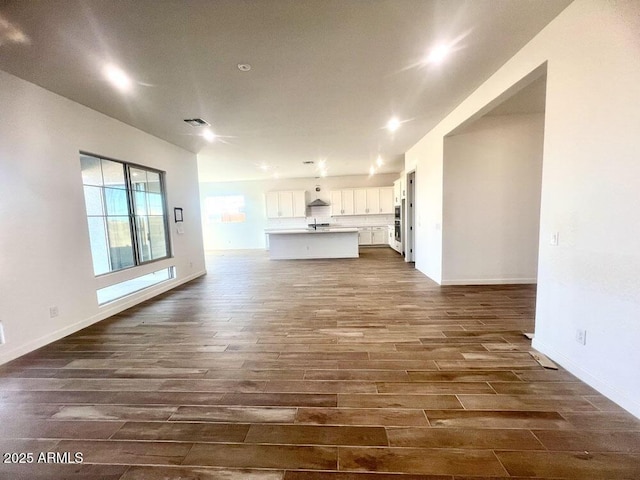 unfurnished living room with visible vents, baseboards, and dark wood finished floors