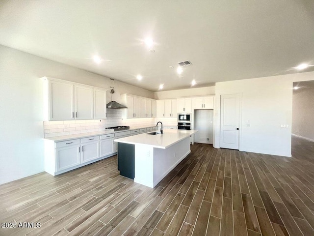 kitchen with visible vents, a sink, backsplash, wood finished floors, and stainless steel appliances