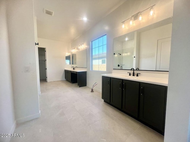 bathroom featuring visible vents, baseboards, two vanities, a stall shower, and a sink