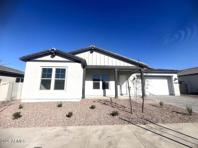 view of front of house with stucco siding, driveway, a garage, and board and batten siding