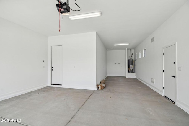 garage with gas water heater, a garage door opener, visible vents, and baseboards