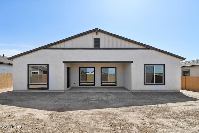 rear view of property with stucco siding and fence