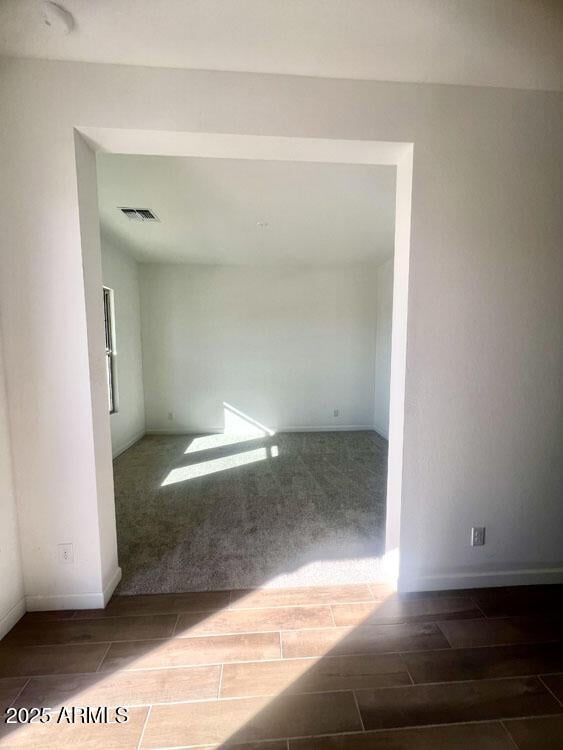 spare room featuring baseboards, visible vents, and wood finish floors