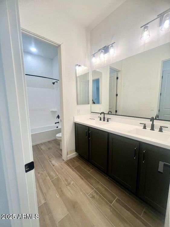 full bath featuring double vanity, toilet, wood tiled floor, and a sink