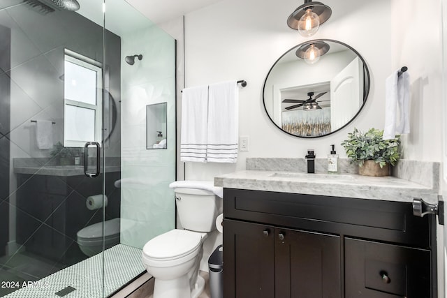 bathroom featuring ceiling fan, vanity, a shower with shower door, and toilet