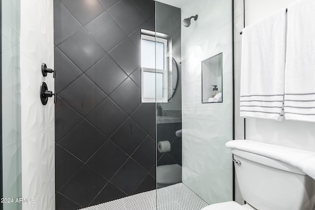 bathroom featuring a tile shower and toilet