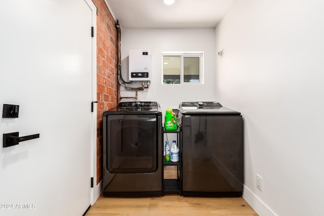 washroom featuring washer and clothes dryer, light hardwood / wood-style flooring, and tankless water heater