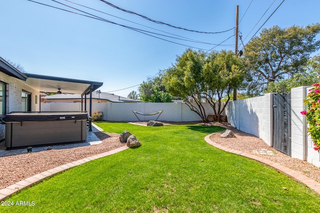 view of yard with ceiling fan and a hot tub