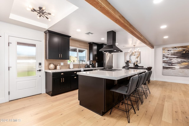 kitchen featuring light hardwood / wood-style floors, an inviting chandelier, a kitchen island, a breakfast bar, and island range hood