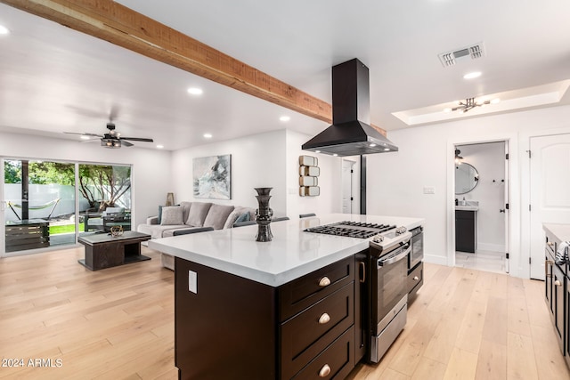 kitchen featuring beam ceiling, island range hood, light hardwood / wood-style flooring, a center island, and stainless steel range with gas cooktop