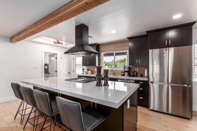 kitchen featuring decorative backsplash, a center island, island range hood, light hardwood / wood-style flooring, and appliances with stainless steel finishes