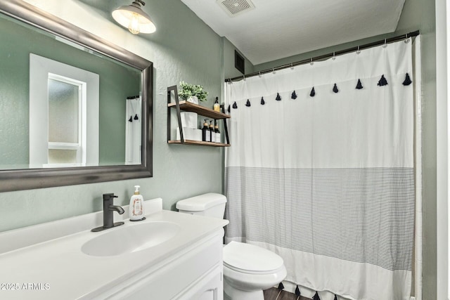 bathroom with visible vents, a textured wall, vanity, and toilet