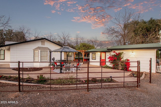 view of front of home featuring an outbuilding, a patio, metal roof, and a gazebo