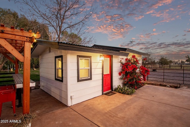 outdoor structure at dusk with fence and a pergola