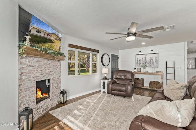 living area featuring visible vents, a fireplace, a textured ceiling, and wood finished floors