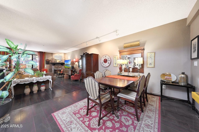 dining area with track lighting, a textured ceiling, and wood finished floors