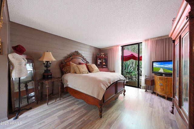 bedroom featuring a textured ceiling, wood finished floors, access to exterior, and wood walls