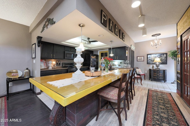kitchen featuring appliances with stainless steel finishes, a textured ceiling, light wood-type flooring, a chandelier, and hanging light fixtures