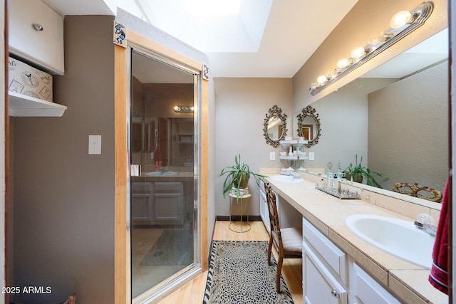 full bath with a stall shower, wood finished floors, double vanity, and a skylight