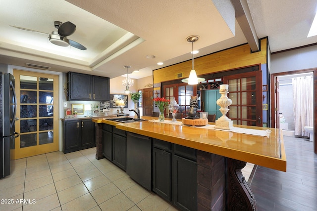 kitchen with a sink, freestanding refrigerator, wood counters, a ceiling fan, and decorative light fixtures