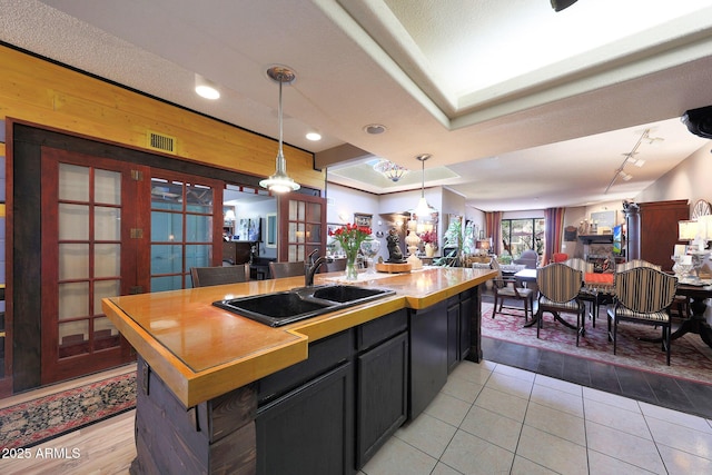 kitchen featuring a sink, open floor plan, hanging light fixtures, a center island with sink, and light tile patterned floors