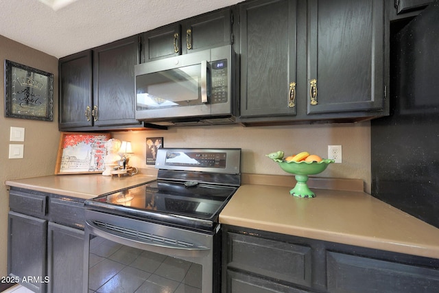 kitchen featuring stainless steel appliances, light countertops, tile patterned flooring, and a textured ceiling