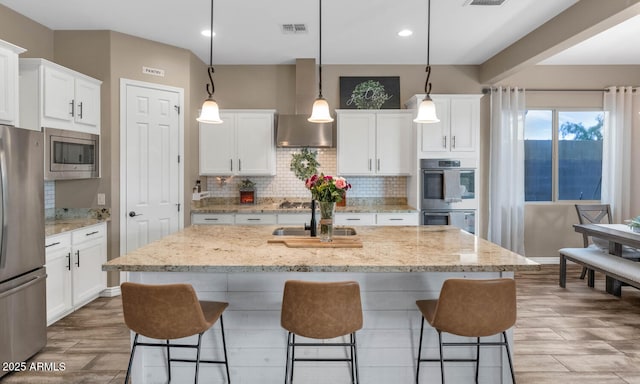 2605 W Desert Marigold Dr, Phoenix, AZ 85085 - kitchen with a kitchen bar, wall chimney range hood, visible vents, appliances with stainless steel finishes, and a sink