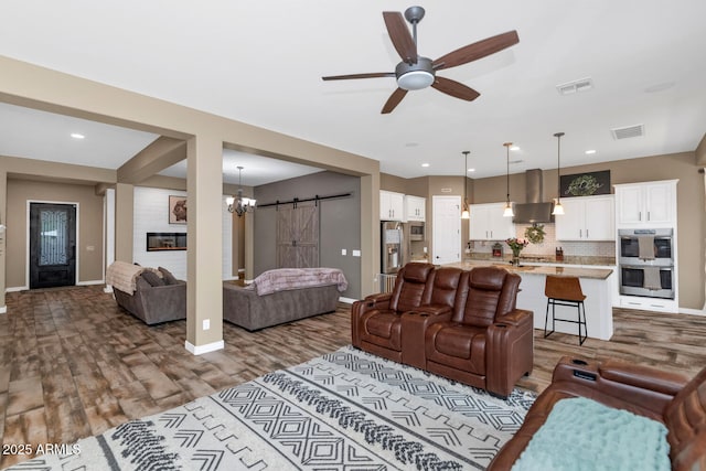 2605 W Desert Marigold Dr, Phoenix, AZ 85085 - living area featuring baseboards, a ceiling fan, a barn door, visible vents, and wood finished floors