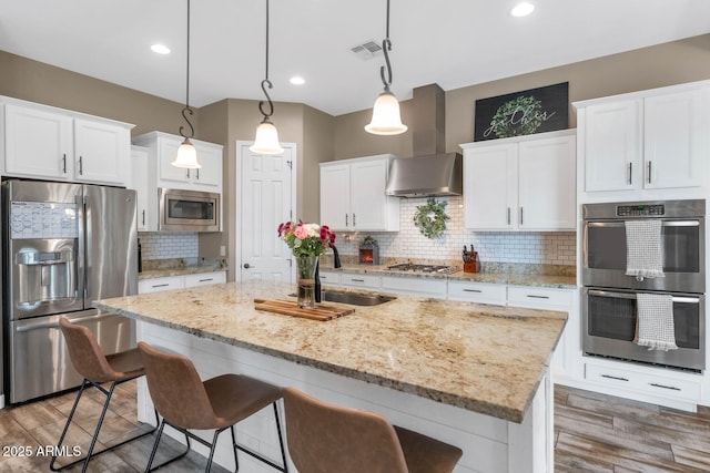 2605 W Desert Marigold Dr, Phoenix, AZ 85085 - kitchen with stainless steel appliances, white cabinets, wall chimney exhaust hood, and a kitchen bar
