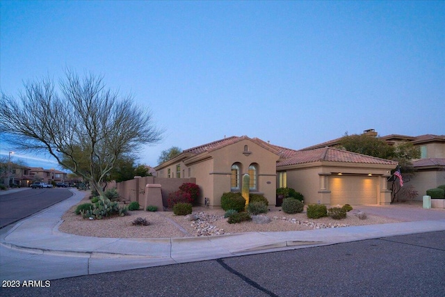 mediterranean / spanish-style home featuring stucco siding, fence, a garage, driveway, and a tiled roof