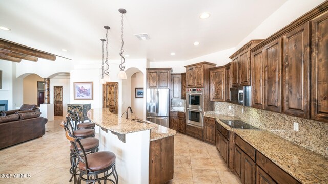 3168 S Yaqui Ln, Gold Canyon, AZ 85118 - kitchen featuring appliances with stainless steel finishes, a breakfast bar, sink, light stone counters, and a spacious island
