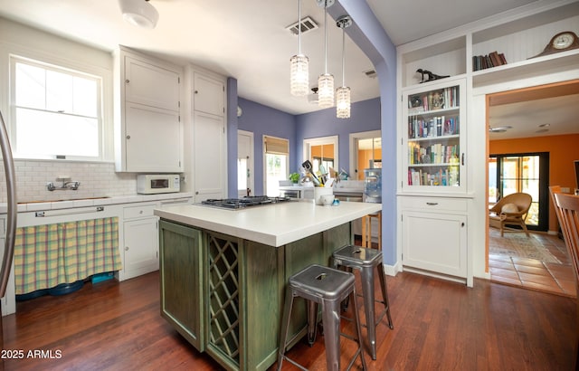 39 E Hoover Ave, Phoenix, AZ 85004 - kitchen with visible vents, stainless steel gas cooktop, light countertops, white microwave, and a breakfast bar