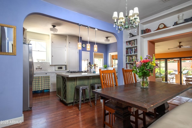 39 E Hoover Ave, Phoenix, AZ 85004 - dining space featuring built in features, arched walkways, ceiling fan with notable chandelier, and dark wood-style floors