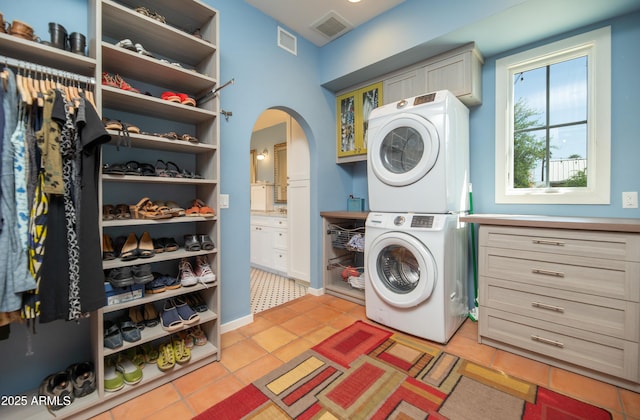 39 E Hoover Ave, Phoenix, AZ 85004 - clothes washing area with cabinet space, stacked washer and dryer, arched walkways, and visible vents