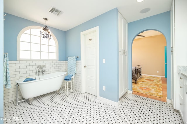 39 E Hoover Ave, Phoenix, AZ 85004 - full bath with an inviting chandelier, a wainscoted wall, a freestanding tub, tile walls, and visible vents