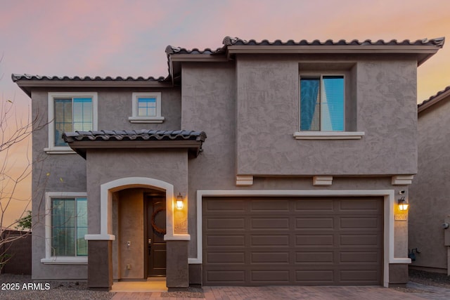 view of front of home with a garage, a tile roof, and stucco siding