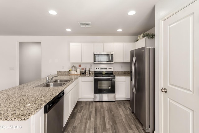 kitchen featuring a peninsula, white cabinetry, appliances with stainless steel finishes, and a sink